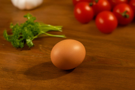 A single brown egg on a wooden surface with fresh ingredients