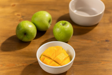 Mango in a Bowl with Green Apples on a Wooden Tableの写真素材