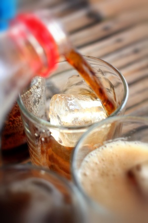 Pouring a glass of soft drink with ice cubesの写真素材