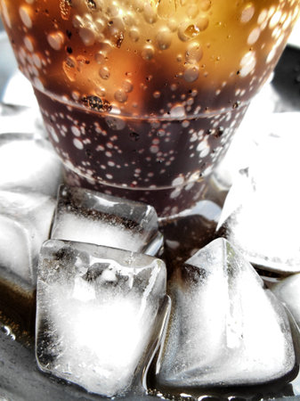 cola with ice cubes on black background