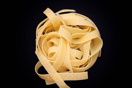 Italian pasta fettuccine nest on black backgroundの写真素材
