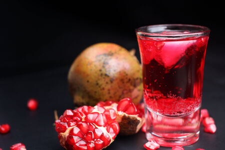 Red pomegranate juice in a glass and half of pomegranateの写真素材