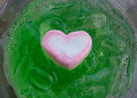 Marshmallows heart on green drinkの写真素材
