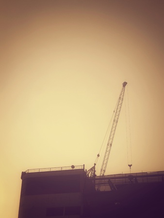 vintage crane and unfinished building at construction siteの写真素材