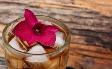 Glass of cola with ice cubes and purple orchid