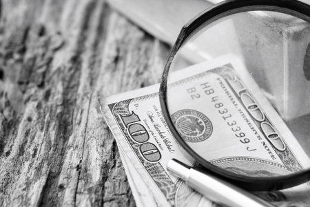 Magnifying glass on american dollars money , pen and books