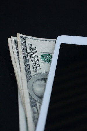 Tablet computer and dollar on black backgroundの写真素材