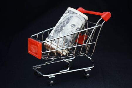 Shopping trolley with dollars on black background - shopping carの写真素材