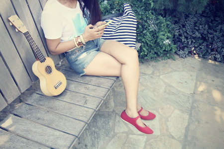 woman using smart phone with ukuleleの写真素材