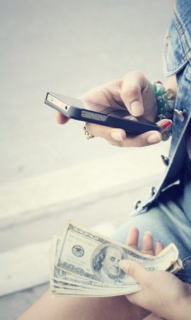 Woman using smart phone with dollarの写真素材