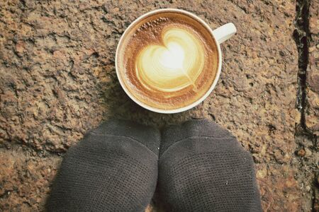 Selfie of latte art coffee with feet relaxingの写真素材