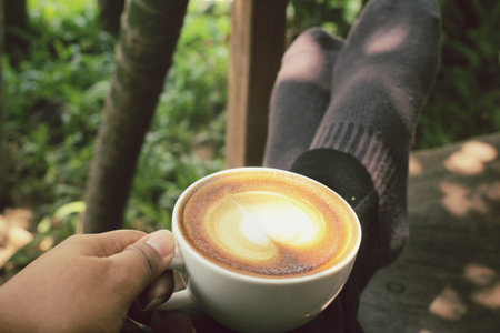 Selfie of latte art coffee with feet relaxing