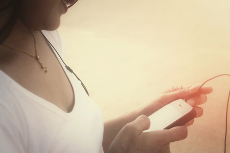 Woman listening to music on earphone with smart phoneの写真素材