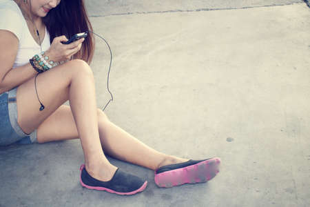 Woman listening to music on earphone with smart phoneの写真素材
