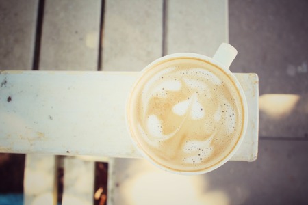 Vintage latte art coffee on chairの写真素材