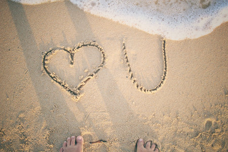 Selfie of word love you written in sand on beach