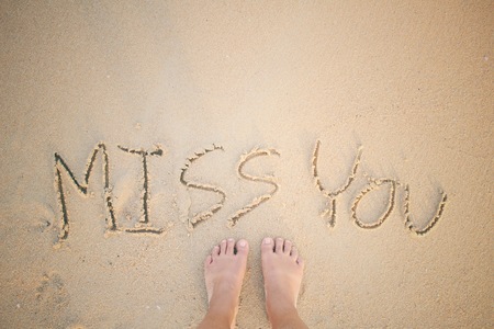 Selfie of word miss you written in sand on beachの写真素材