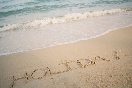 The word holiday written in sand on beachの写真素材