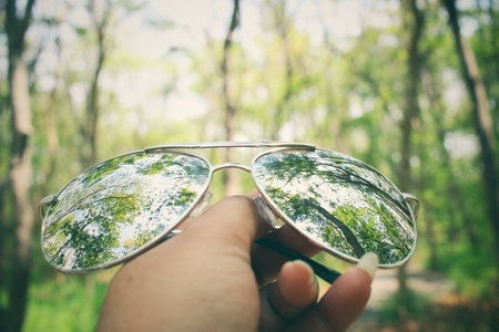 Hand with sun glasses in the forest
