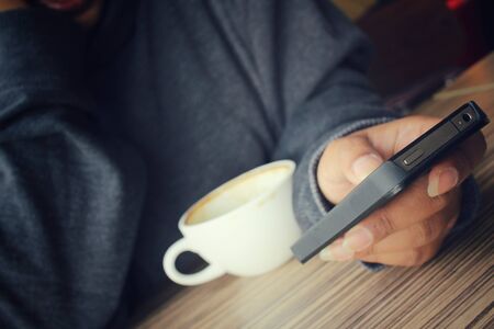 Woman using smart phone with coffee cupの写真素材