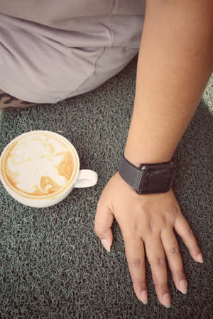 Woman drinking coffee with smartwatchの写真素材