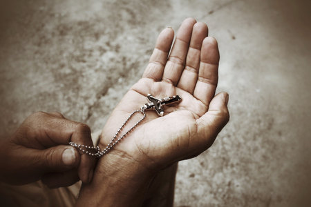 Senior man hands praying with cross