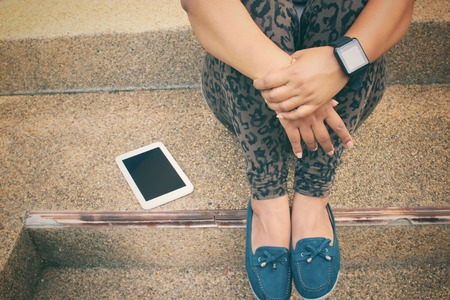 Woman sitting and tablet with smartwatchの写真素材