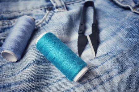 Bobbins threads with scissors on jeansの写真素材