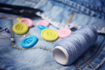 Colorful sewing buttons scissors and thread on jeansの写真素材