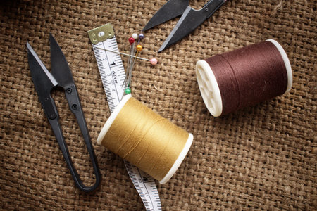 Sewing threads with scissors on sackcloth