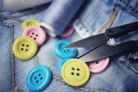 Colorful sewing buttons scissors and thread on jeansの写真素材