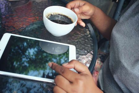 Woman drinking hot coffee with tabletの写真素材