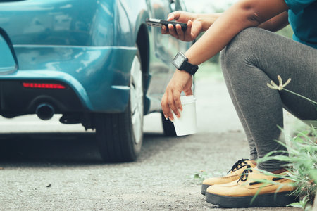 Woman using smart phone and coffee paper cup with car on road
