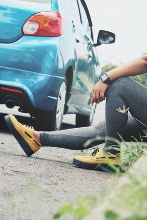 Woman and smart phone with car on roadの写真素材