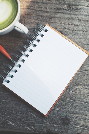 Blank notepad and pen with green tea on office tableの写真素材