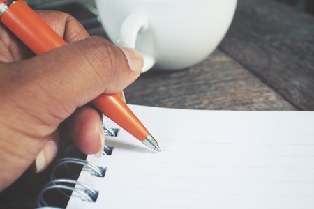 Woman with pen writing on paper at office tableの写真素材