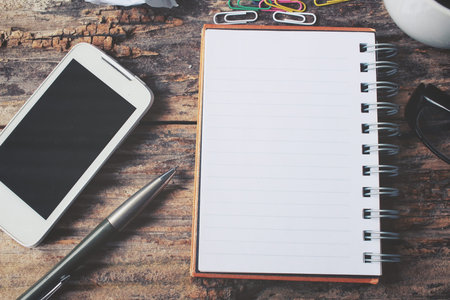 Blank notepad and smart phone on office table