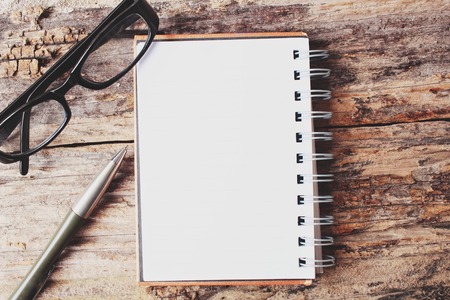 Blank notepad and glasses with pen on office tableの写真素材