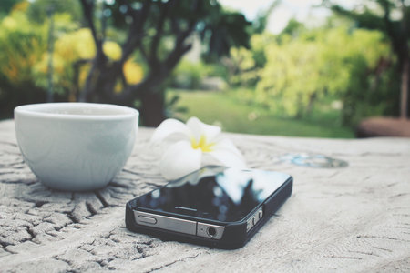 Espresso coffee and frangipani flower with smart phone