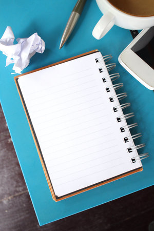 Blank notepad and smartphone with coffee on office table