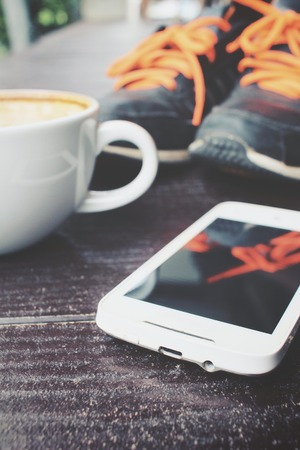 Latte coffee and smartphone with sneakersの写真素材