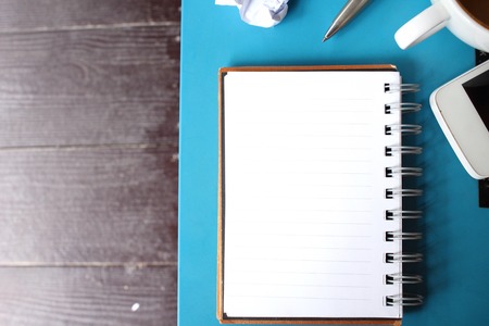 Blank notepad and smartphone with coffee on office tableの写真素材