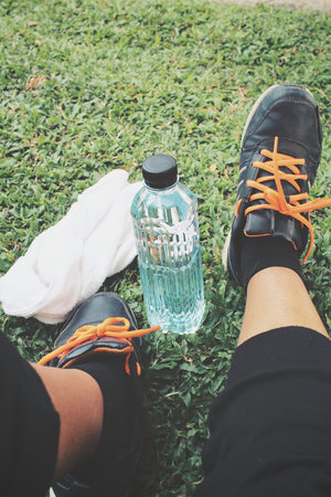 Selfie of shoes and towel with water drink on green grassの写真素材