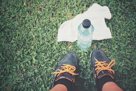 Selfie of shoes and towel with water drink on green grassの写真素材