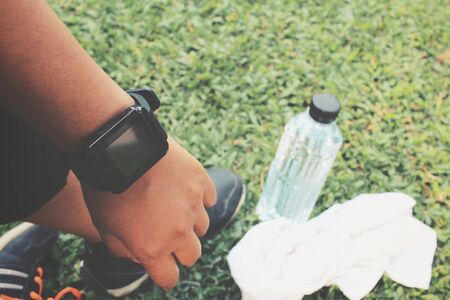 Selfie of smartwatch and sport shoes with water drink on green grassの写真素材