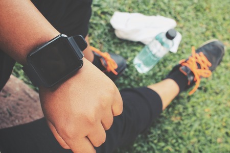 Selfie of smartwatch and sport shoes with water drink on green grassの写真素材