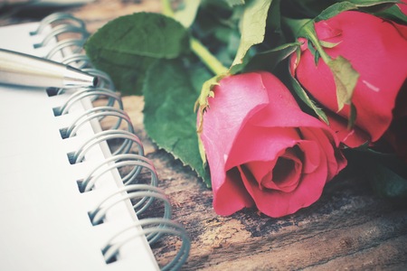 Blank notepad with red rose and penの写真素材