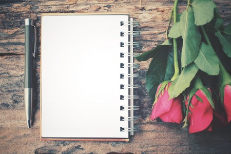 Blank notepad with red rose and penの写真素材