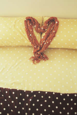 Heart of scarf on bed pillows at hotelの写真素材
