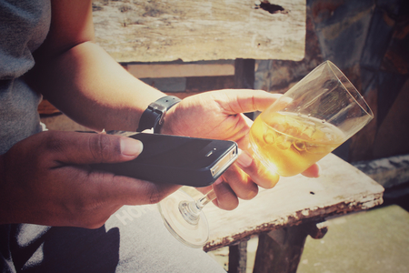 Glasses of brandy with smart phone on handの写真素材